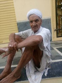 Portrait of senior man sitting on walkway