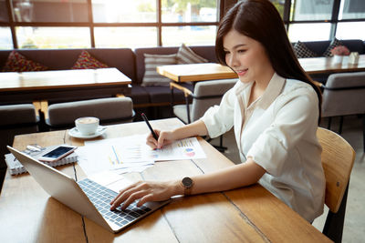 Woman using phone while sitting on table