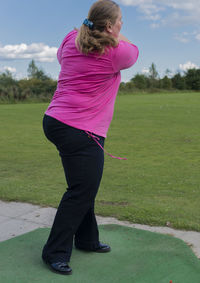 Full length of young woman standing on golf course