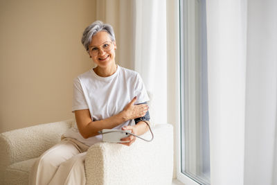 Portrait of young man sitting on bed at home
