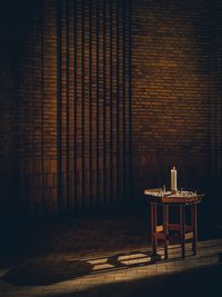 Empty chairs and table against wall at night