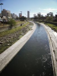 Canal amidst buildings in city against sky