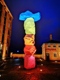 Illuminated sculpture by building against sky at night