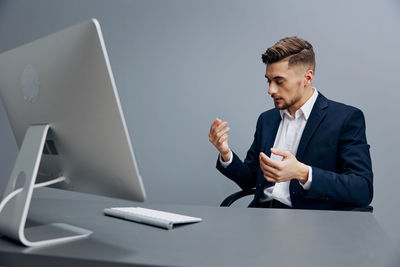 Portrait of young man using laptop while standing in office