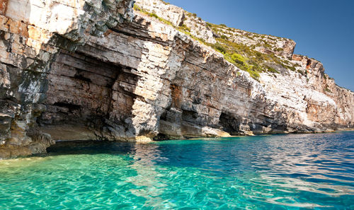 Stone layered structure of island vis and colored geological layers and turquoise water of sea.