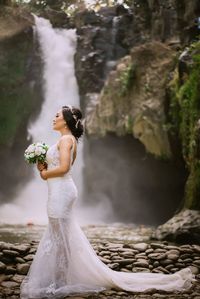 Close-up of woman standing on rock by waterfall