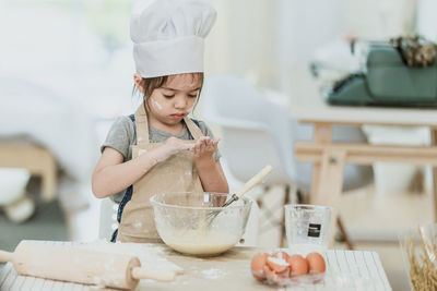 Girl holding ice cream in bowl on table at home