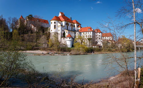 Buildings by river against blue sky