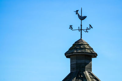 Low angle view of weather vane against blue sky