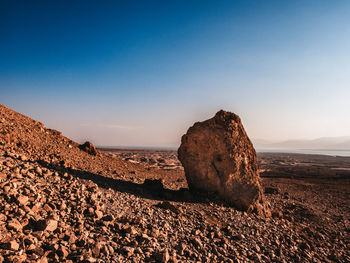 Rock formation on beach against sky during sunset
