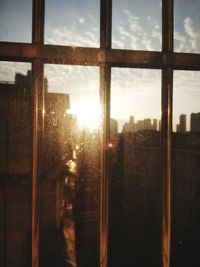 Buildings against sky seen through glass window