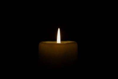 Close-up of lit candle in darkroom