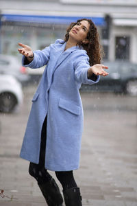 Mature woman wearing blue overcoat during snowfall in city