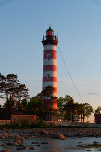 Lighthouse by sea against clear sky