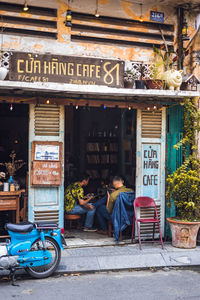 People sitting on street against buildings in city