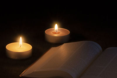 Close-up of lit candles on table in darkroom