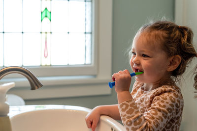 Cute girl brushing teeth at home