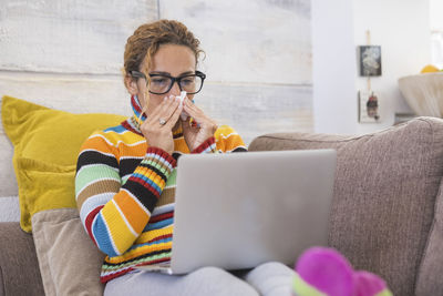 Man using mobile phone while sitting on sofa at home
