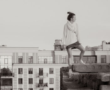 Full length of man jumping against buildings in city