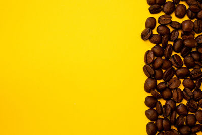 Directly above shot of coffee beans against yellow background