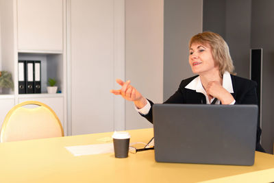 Woman using phone while sitting on table