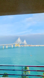 Suspension bridge over sea against sky