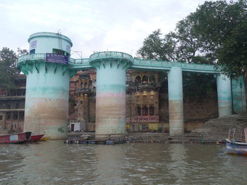 Built structure by river in city against sky