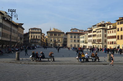 People on town square against sky in city