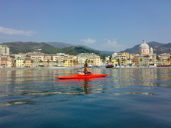 Woman kayaking in sea against mountain