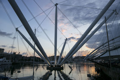 Cranes at harbor against sky at sunset