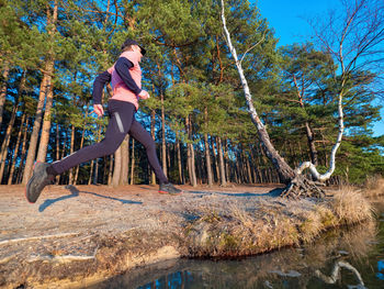 Woman standing by trees in forest