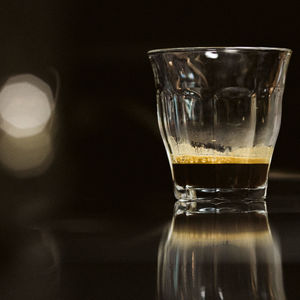 Close-up of beer glass on table against black background