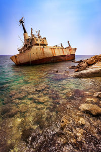 Abandoned ship on beach against sky