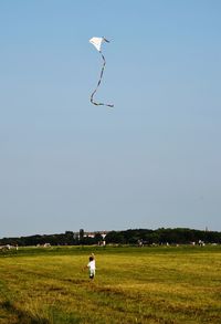 People paragliding on field against clear sky