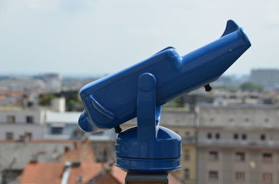 Close-up of coin-operated binoculars against cityscape