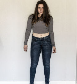 Portrait of young woman standing against wall