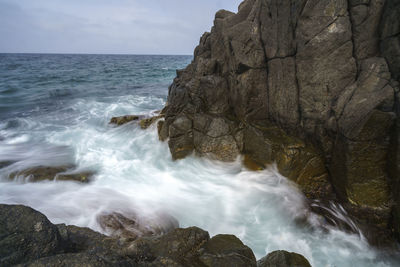 Rock formation in sea against sky