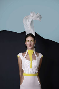 Portrait of beautiful young woman standing against wall