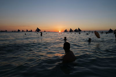 Silhouette man on sea against sky during sunset