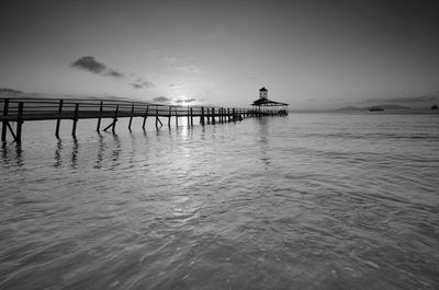 Silhouette pier over sea against sky