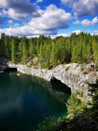 A picturesque view of the lake among the trees in the forest against the backdrop of the sky 