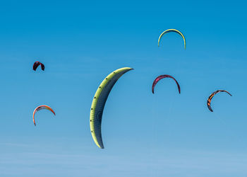 Low angle view of person paragliding against clear blue sky