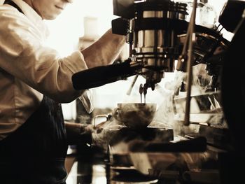 Midsection of barista preparing coffee in cafe