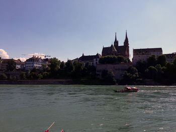 Boat in river by building against clear sky