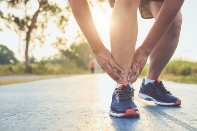 Low section of man in sports shoes on road