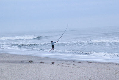 Fishermen on the beach.man standing on beach against clear sky