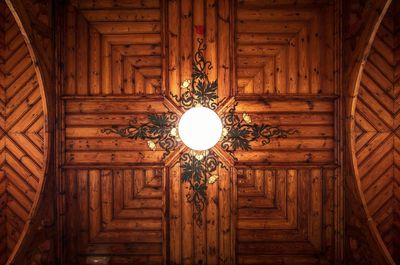 Directly below shot of lamp on wooden ceiling at home