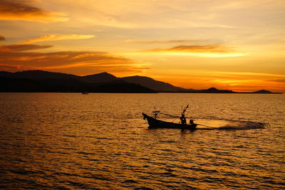 Silhouette boat in sea against orange sky