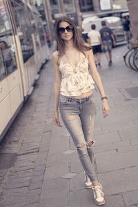 Full length portrait of fashionable woman standing on footpath