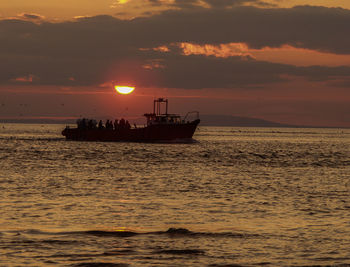 Silhouette boat in sea against sky during sunset